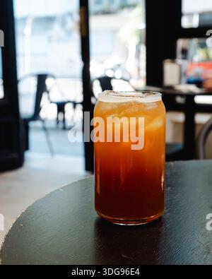 Café americano glacé placé sur une table noire, avec un intérieur de café flou en arrière-plan Banque D'Images