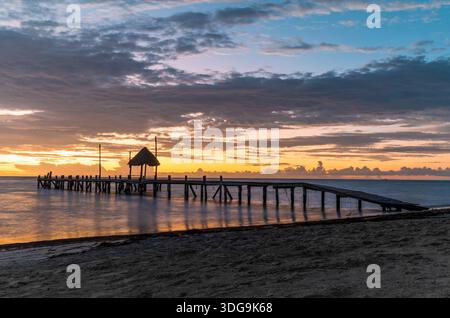 Un lever de soleil magnifique et coloré sur une jetée en bois sur la plage de Cancun, au Mexique. Banque D'Images