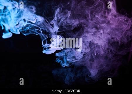 Fumée colorée mélangeant vapeur bleue et violette Banque D'Images