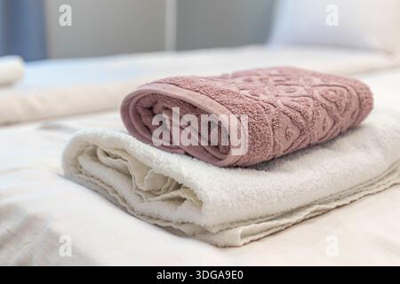 serviettes beige blanches et roses pliées sur le lit dans la chambre d'hôtes pour le client de l'hôtel Banque D'Images