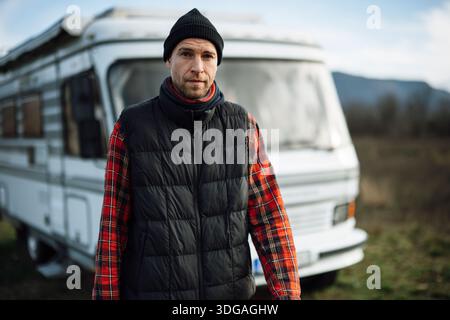 L'homme se tient devant le camping-car portant une chemise à carreaux Banque D'Images