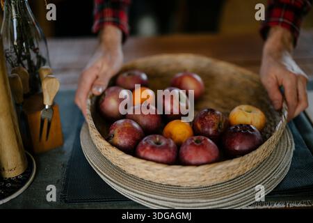 Personne plaçant un panier de pommes sur une table en bois Banque D'Images