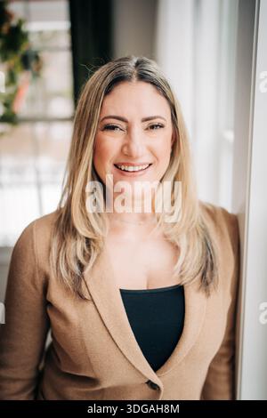 Femme souriant dans le portrait blazer d'affaires à l'intérieur Banque D'Images