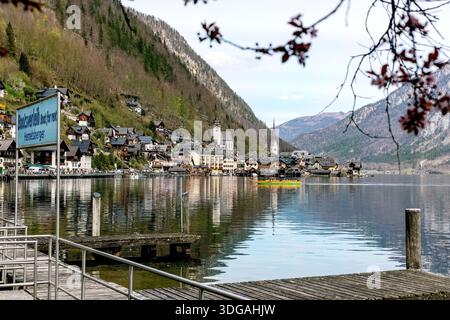 Vue panoramique sur le village de Hallstatt en Autriche avec des maisons traditionnelles nichées entre les montagnes et le lac. Église flèches quai en bois au premier plan calme w Banque D'Images