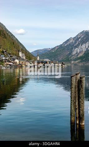Vue panoramique sur le village de Hallstatt avec des maisons traditionnelles et des tours d'église reflétées dans les eaux calmes du lac entouré par les montagnes majestueuses des Alpes à Aust Banque D'Images