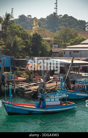 Thaïlande, Ko Kood, Ao Salad, bateaux de pêche amarrés à la jetée en bois sous bouddha géant Banque D'Images