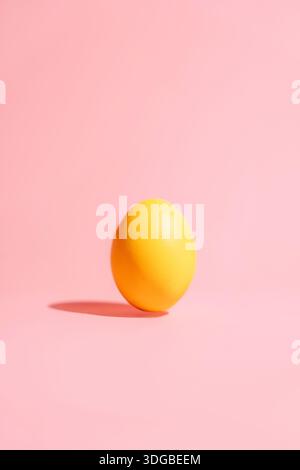 Oeuf de Pâques jaune unique sur fond rose, espace de copie vertical minimal Banque D'Images