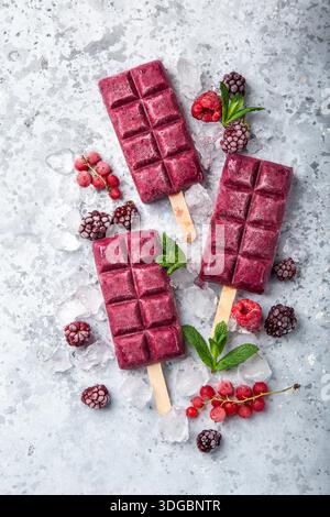 baies crème glacée popsicles avec des baies congelées sur fond gris, vue de dessus Banque D'Images