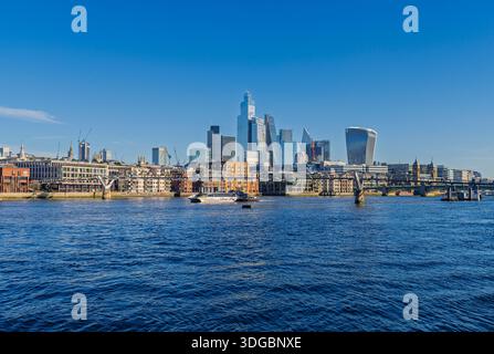 Un bateau Uber passe sous le Millenium Bridge sur la Tamise devant les gratte-ciel du quartier financier de la City of London, en Angleterre Banque D'Images