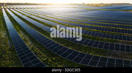 Paysage panoramique aérien de rangées de panneaux solaires photovoltaïques générant de l'énergie propre et renouvelable sur des terres agricoles agricoles avec coucher de soleil et copie s. Banque D'Images
