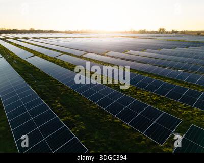 Paysage panoramique aérien de rangées de panneaux solaires photovoltaïques générant de l'énergie propre et renouvelable sur des terres agricoles agricoles avec coucher de soleil et copie s. Banque D'Images