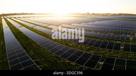 Paysage panoramique aérien de rangées de panneaux solaires photovoltaïques générant de l'énergie propre et renouvelable sur des terres agricoles agricoles avec coucher de soleil et copie s. Banque D'Images