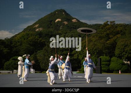 Séoul, Corée du Sud : groupe coréen de percussions traditionnelles exécutant la danse samulnori avec des tambours et des chapeaux sur fond de montagne Banque D'Images