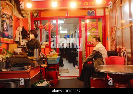 Séoul, Corée du Sud : restaurant de rue coréen local avec cuisinier préparant la nourriture et clients assis dans un petit restaurant traditionnel Banque D'Images