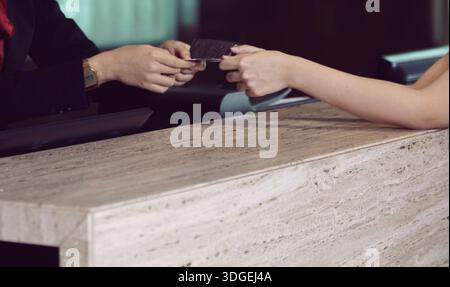 Deux mains échangent une carte de visite et des transactions, mettant en évidence le réseautage, le contact professionnel et la collaboration entre les individus. ECHANGE personnel Banque D'Images