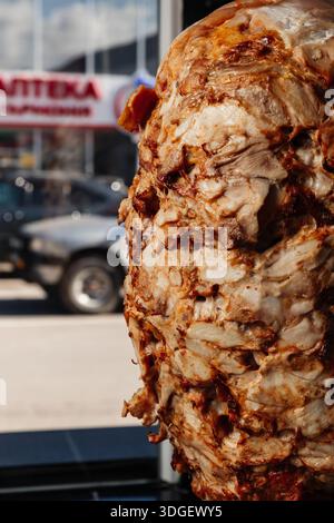 Une rôtisserie verticale fait tourner des couches de viande assaisonnée pour le shawarma. Banque D'Images