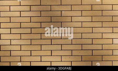 Mur lisse en brique brun clair dans un éclairage doux ensoleillé avec des taches d'ombres lisses sur la surface, fond texturé géométrique de blocs rectangulaires Banque D'Images