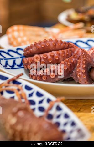 Tentacules de pieuvre cuits servis dans une assiette blanche à motifs Banque D'Images