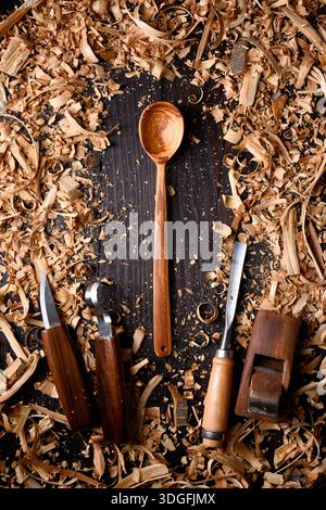 Cuillère en bois artisanale avec tas de limailles en bois avec différents outils de menuiserie manuelle. Concept de fabrication artisanale Banque D'Images