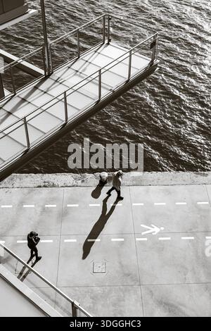 Santander, Espagne – 20 novembre 2021 : vue de haut en bas noir et blanc d’une personne prenant une photo sur la promenade du front de mer avec une longue ombre projetée par le L. Banque D'Images