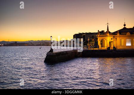Le Palacete del Embarcadero illuminé sur le front de mer de Santander, Espagne, pendant un beau crépuscule avec un ciel doré coucher de soleil sur la baie. Banque D'Images