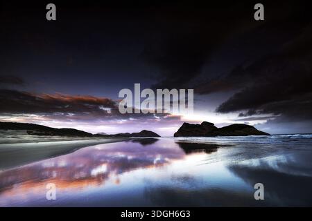 Coucher de soleil spectaculaire sur la plage de Wharariki avec un reflet impressionnant dans l'eau, Wharariki, Tasman, Nouvelle-Zélande Banque D'Images