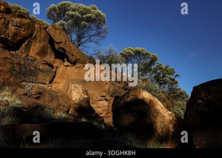 Formations rocheuses massives avec végétation clairsemée et ciel bleu profond, Palm Valley, territoire du Nord, Australie Banque D'Images