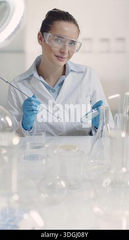 Une scientifique travaillant dans un laboratoire trace une culture bactérienne sur une plaque de gélose à l'aide d'une boucle d'inoculation. Microbiologie, biotechnologie, médical, a Banque D'Images