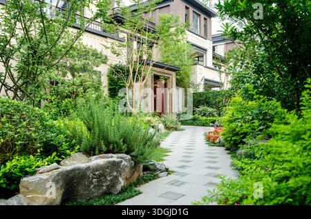 Vue de face d'une villa de luxe avec un chemin de pierre sinueux, de grands rochers décoratifs et un paysage verdoyant. La conception met l'accent sur privac Banque D'Images
