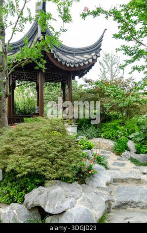 Plan vertical d'un jardin chinois traditionnel avec un pavillon hexagonal en bois avec un toit incurvé. Au premier plan, de grandes pierres grises de rocaille a Banque D'Images
