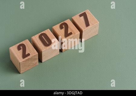 Cubes en bois avec les numéros 2027 sur fond vert. Concept du nouvel an Banque D'Images