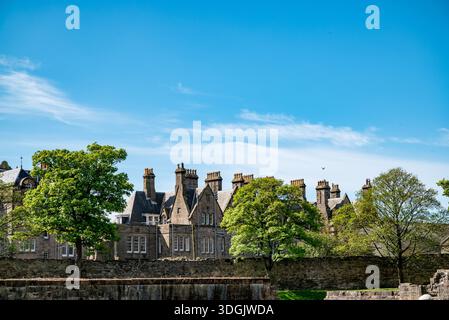 Un grand plan de grands bâtiments historiques en pierre dans le complexe Andrews avec des pots de cheminée traditionnels et des arbres verdoyants dans un ciel dégagé. Banque D'Images