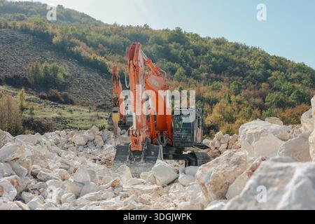 Excavatrice opérant parmi de grands blocs de pierre en terrain montagneux Banque D'Images