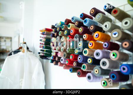 Bobines de fil de différentes couleurs soigneusement disposées sur des étagères en bois, créant un affichage visuellement attrayant pour les projets de couture et de confection ou le facil Banque D'Images