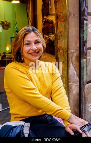 Femme souriante portant un pull jaune dans la rue urbaine Banque D'Images