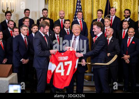 Washington, États-Unis d'Amérique. 15 janvier 2026. Le président américain Donald Trump, au centre, tient un maillot et un bâton de hockey en or, alors qu'il pose avec Matthew Tkachuk, à droite, et le capitaine de l'équipe Aleksander Barkov, à gauche, lors d'un événement célébrant le champion de la Coupe Stanley 2025, Florida Panthers, à la salle est de la Maison Blanche, le 15 janvier 2026, à Washington, DC crédit : Molly Riley/White House photo/Alamy Live News Banque D'Images