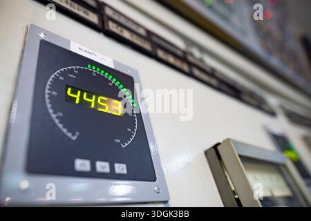 Vue rapprochée et sélective d'un tachymètre numérique sur un panneau de commande industriel. L'affichage LED jaune indique « 445 » tr/min, avec une barre verte Banque D'Images
