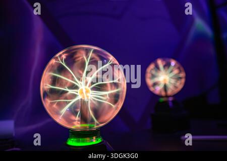 Deux lampes à boules de plasma fonctionnant dans l'obscurité. Chaque globe montre des filaments électriques, démontrant l'excitation de gaz inertes par une haute tension, hig Banque D'Images