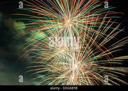 Des feux d'artifice colorés brillants explosent dans le ciel nocturne sombre lors d'une célébration de vacances créant une atmosphère magique de joie et de bonheur pour le nouvel an p. Banque D'Images
