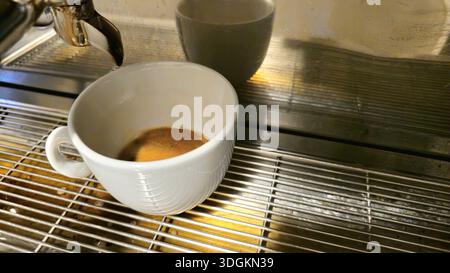 Espresso fraîchement préparé dans une tasse blanche sur une machine à café Banque D'Images