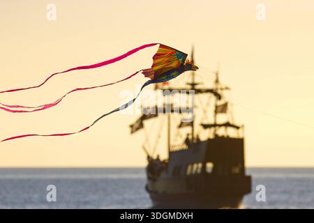 Treasure Island, Floride, États-Unis. 17 janvier 2026. Un cerf-volant en forme de phénix survole la plage de Treasure Island au coucher du soleil devant l'emblématique réplique du navire pirate Royal Conquest de 46 mètres. D'une raie manta de 21 mètres de long à un cerf-volant de deux pouces, professionnels et amateurs participent au festival annuel Treasure Island Kite Festival. (Crédit image : © Zoraida Diaz/ZUMA Press Wire) USAGE ÉDITORIAL SEULEMENT ! Non destiné à UN USAGE commercial ! Banque D'Images