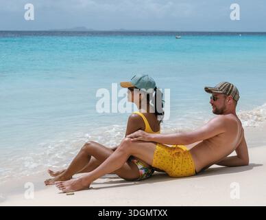 Un couple profite d’un moment de sérénité sur une plage de sable à Curaçao, entourée d’eaux turquoises et d’un ciel dégagé. Cette scène idyllique capture l'essence o Banque D'Images