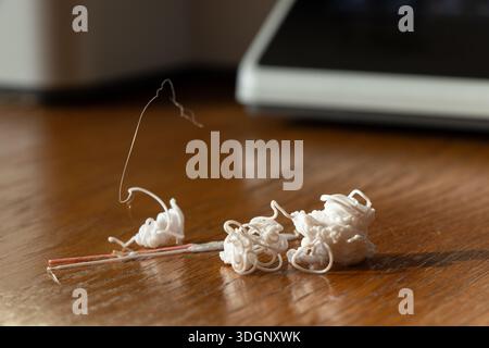 Résidus de plastique provenant de l'impression 3D sur une table en bois, brins et amas de filaments, déchets de production, flux de travail, consommation de matières premières et sortie de l'imprimante Banque D'Images
