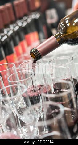 Vin rouge versé dans plusieurs verres lors d'un événement. Banque D'Images