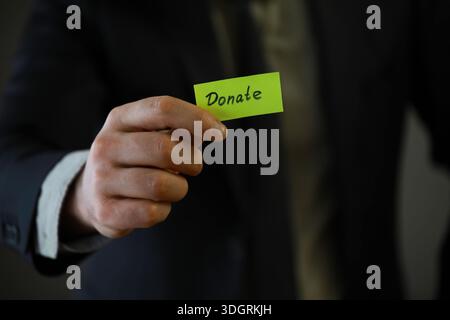 Homme d'affaires montre un bloc de bois avec le mot donner. Don de bienfaisance dans le concept d'affaires. Banque D'Images