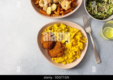 Dégustez un repas savoureux composé de riz garni d'œufs frits à la rhubarbe, de patates douces cuites au four et de légumes colorés. Salade fraîche et beignets de viande croustillants c Banque D'Images