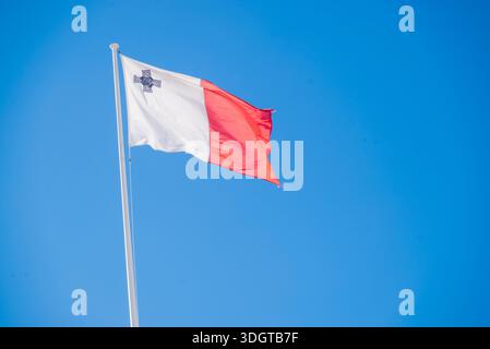 Le drapeau national de Malte contre un ciel bleu Banque D'Images