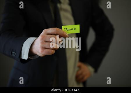 Homme d'affaires montre un bloc de bois avec le mot donner. Don de bienfaisance dans le concept d'affaires. Banque D'Images
