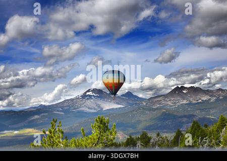 La montgolfière bénéficie d'une vue imprenable sur Three Sisters et Broken Top, alors qu'elle vole au-dessus du mont Bachelor. Ballon est rayé dans des couleurs arc-en-ciel. Banque D'Images