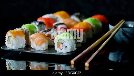 Rouleaux de poisson colorés sur une surface élégante, assortis de sushis de fruits de mer présentés artistiquement avec des garnitures Banque D'Images